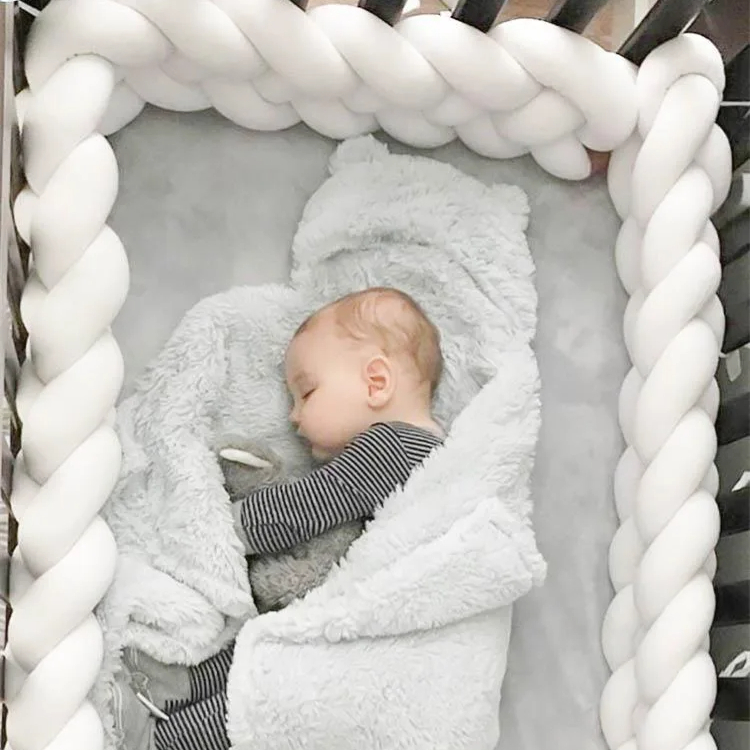  Réducteur de Lit Blanc et Tressé en Coton sur un lit avec un bébé en train de dormir