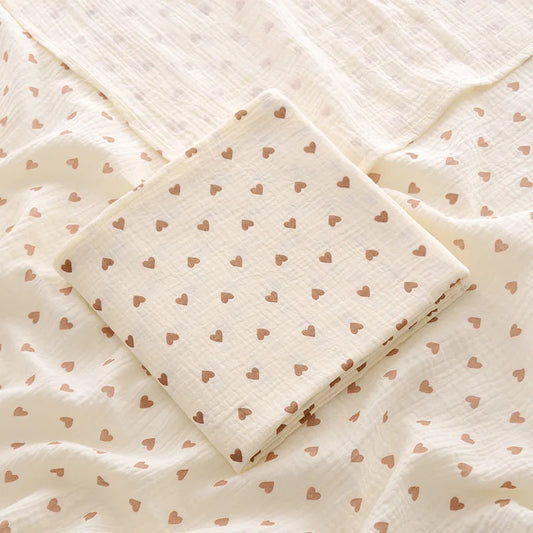 Serviette Bébé avec Motifs de Cœurs pliée sur un lit